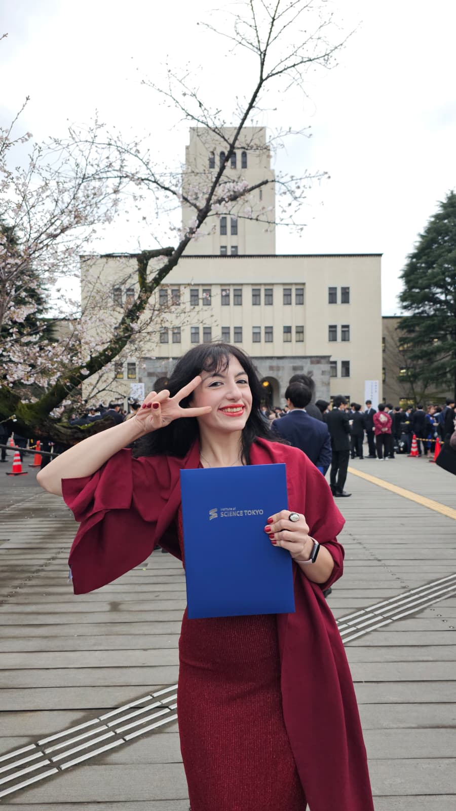 Ece Naz Sefercioğlu holding her Institute of Science Tokyo certificate in front of the university building